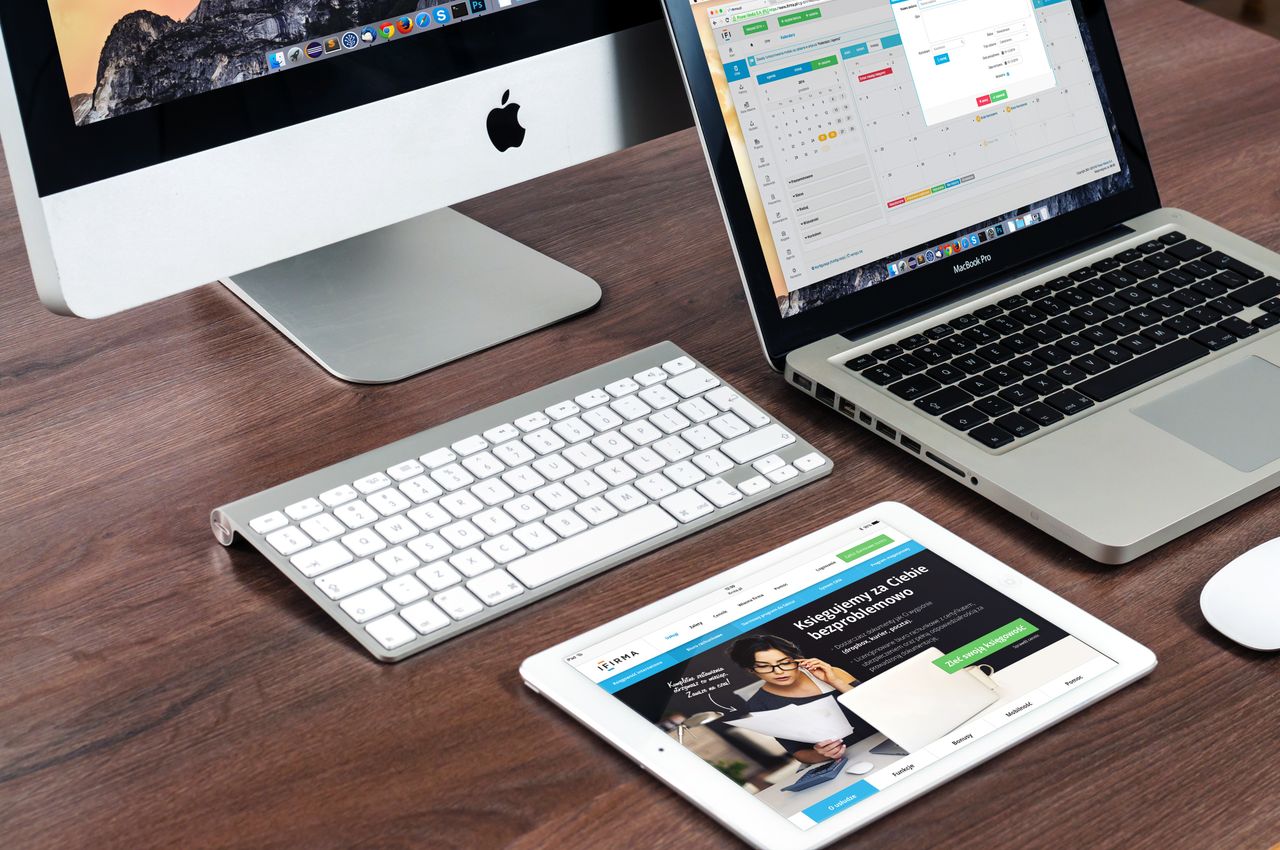 Una configurazione elegante di scrivania per ufficio con dispositivi Apple: iMac, MacBook e iPad.